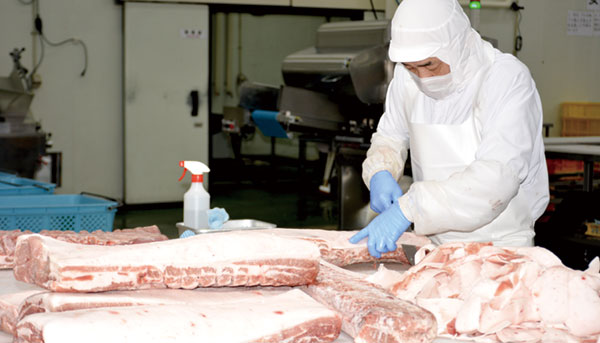 大きな肉の塊から余分な脂身を取り除く整形作業